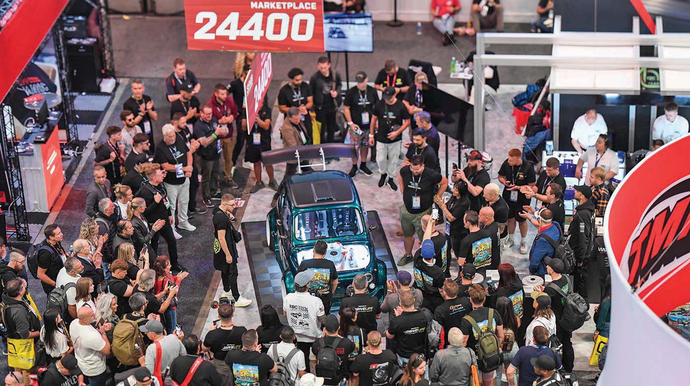 Aerial view of a booth at the SEMA Show with large crowd gathered.
