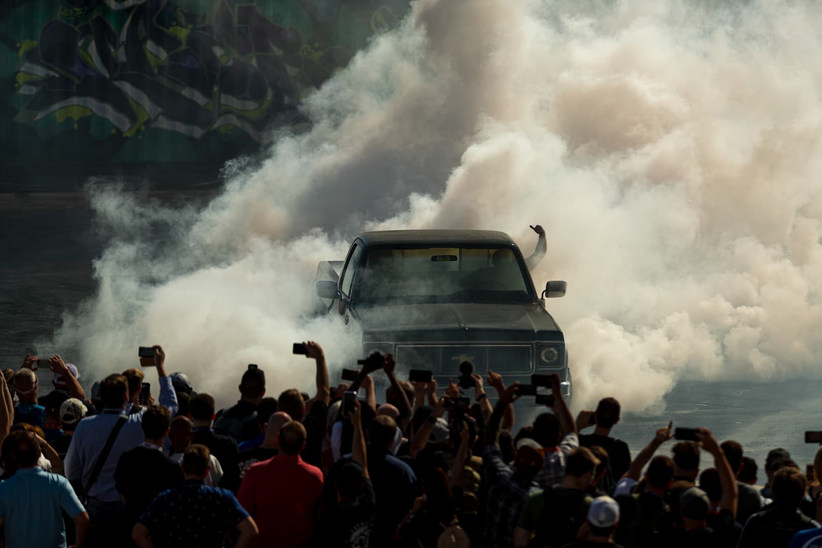 Burnout demonstration truck surrounded by crowd and smoke