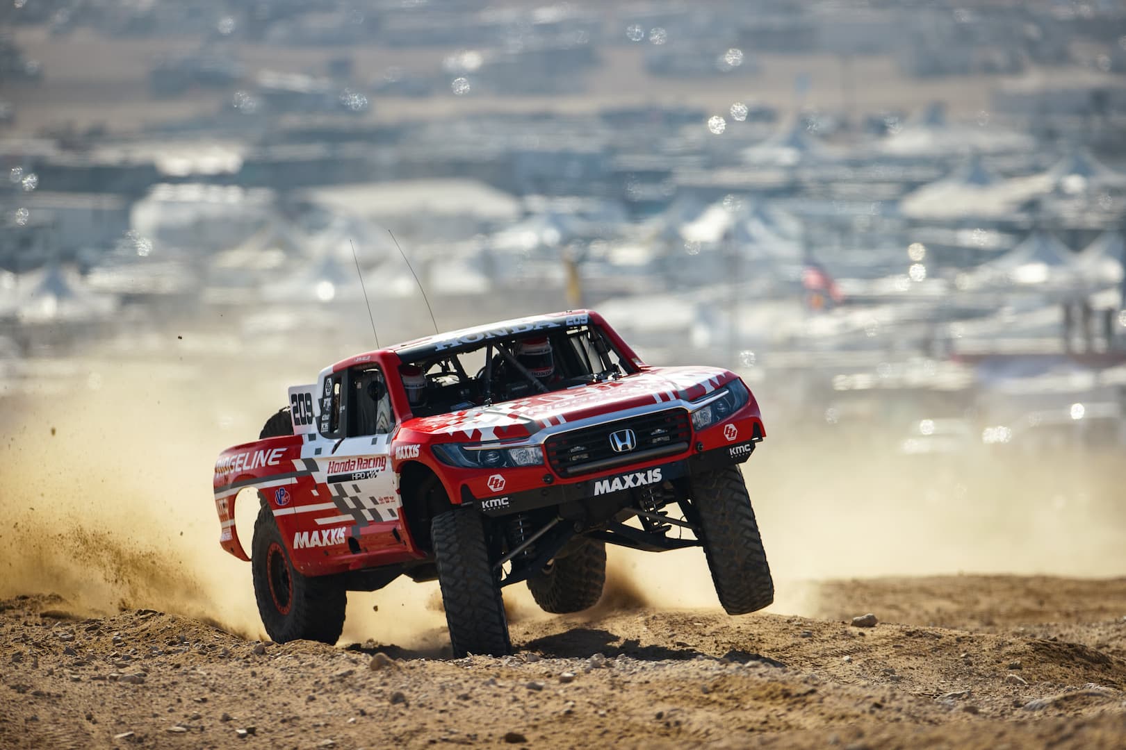 Red Honda off-road race truck in action on a dirt course