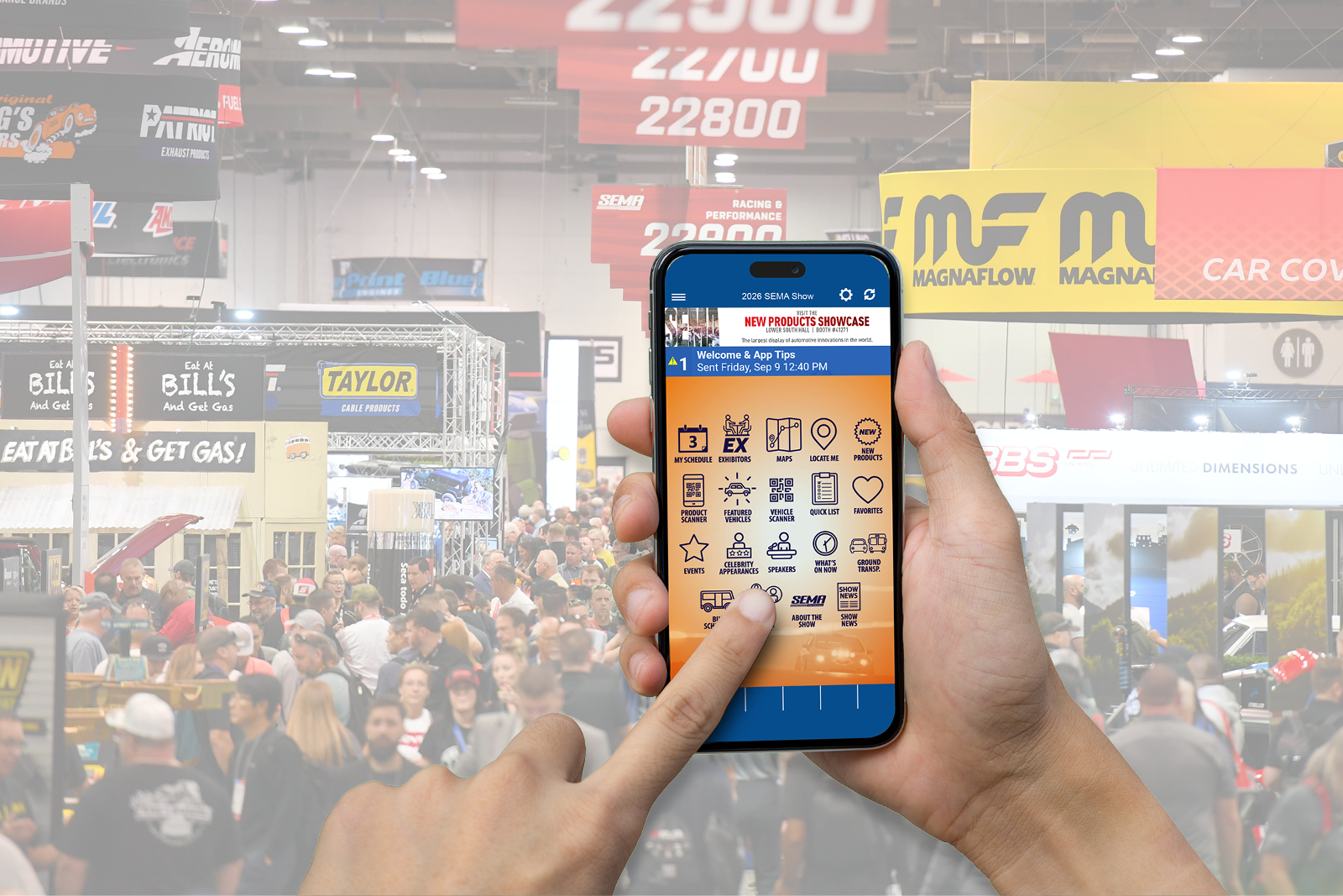 Person holding up smart phone using SEMA SHOW app. Blurred show activity in the background.