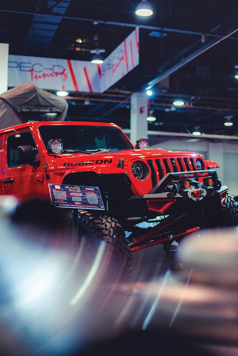 Red Jeep Wrangler Rubicon with a lifted suspension and front bumper on display on the show floor